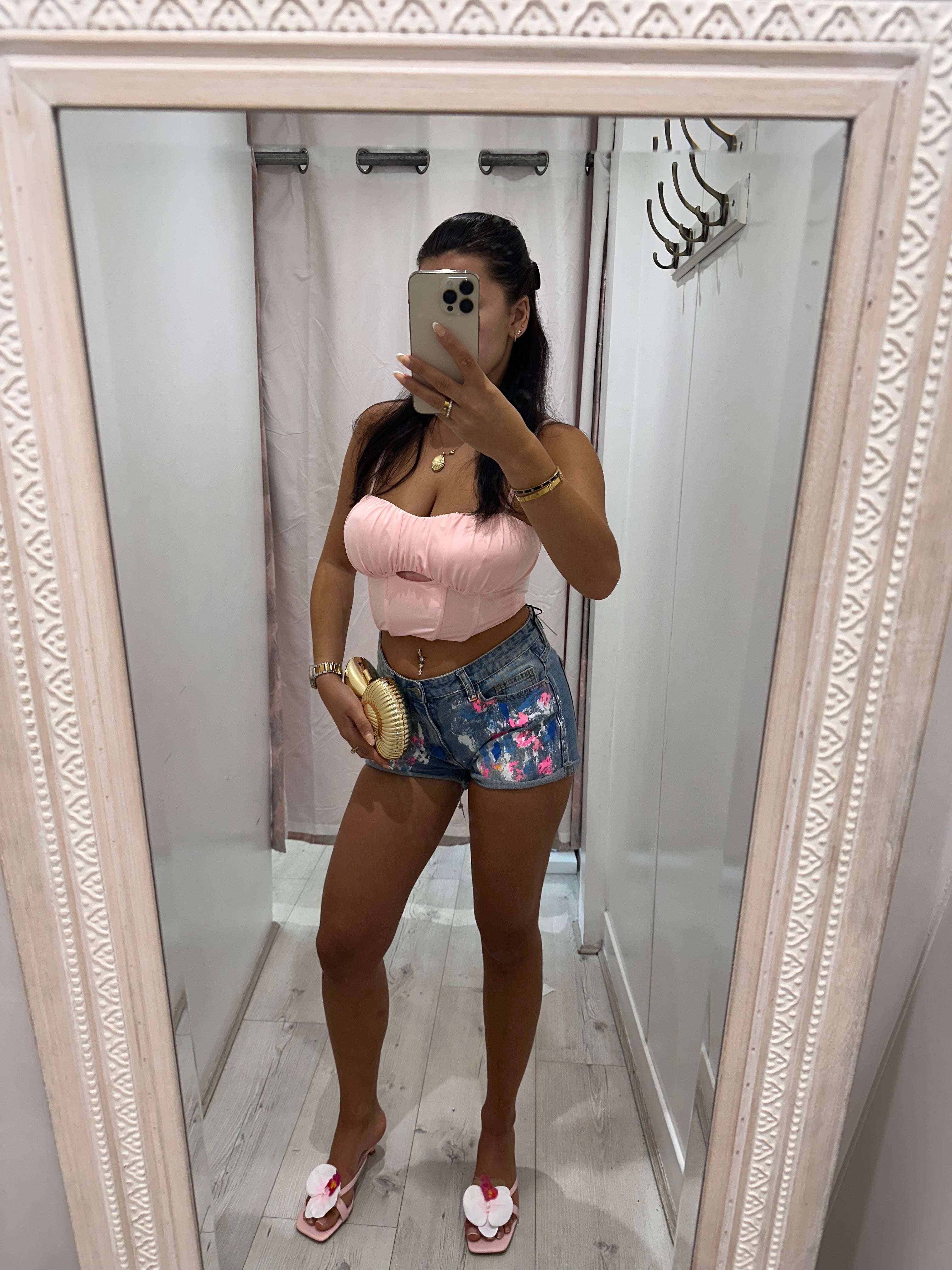 Woman wearing ANGEL Painted Denim Shorts with floral design on a sunny day