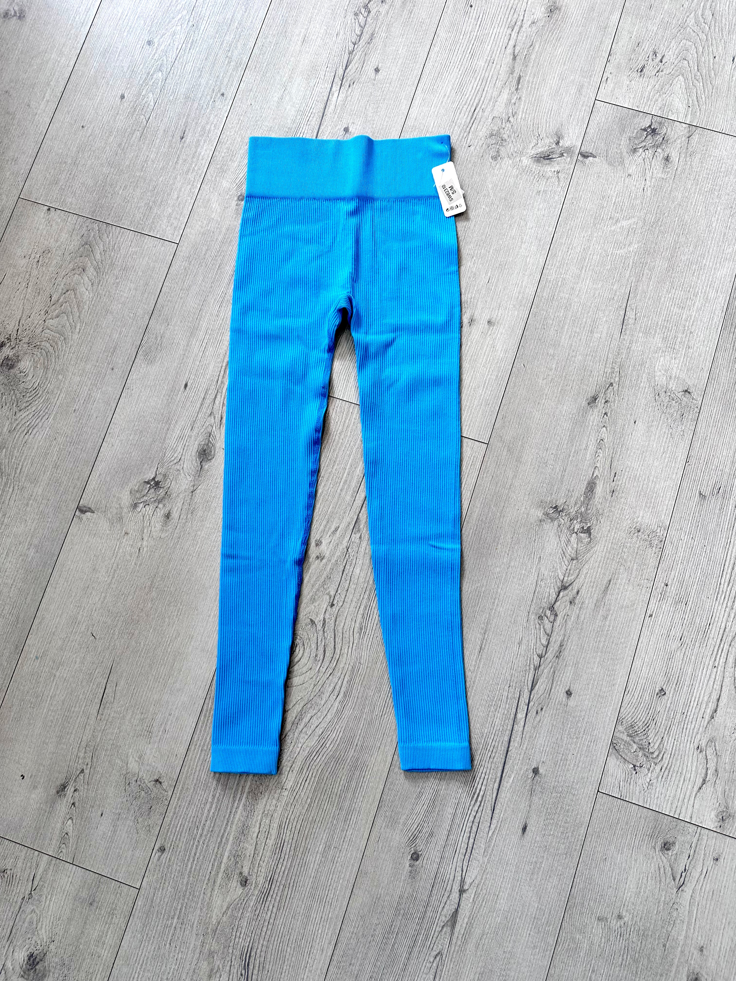 Bright blue ribbed seamless high-waist leggings for women displayed flat on light wood flooring, featuring a V-contour waistband and soft stretch fabric