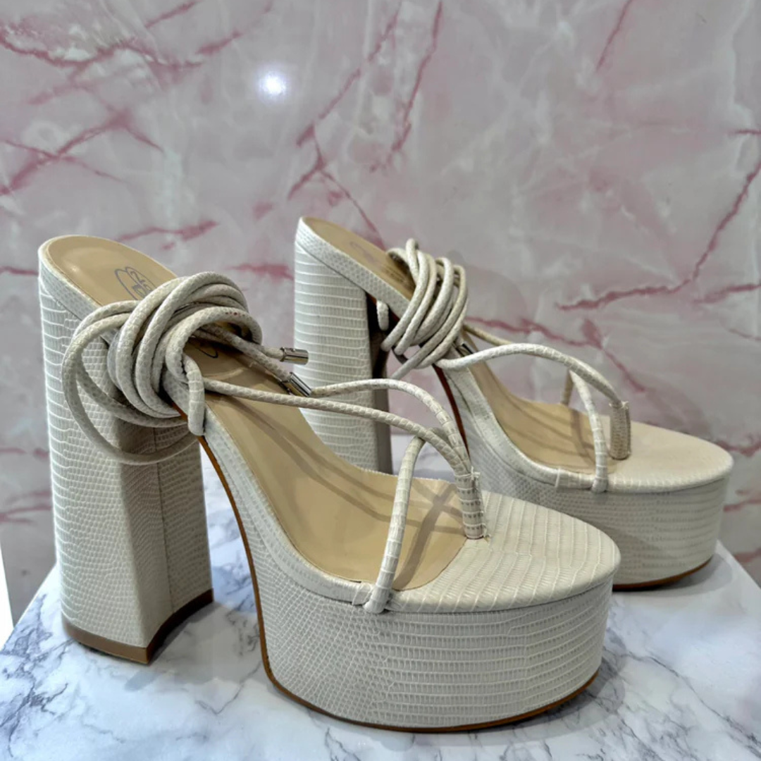Cream lizard print platform heels with ankle tie-up straps and chunky block heel, elegant high heel sandals for women on marble background