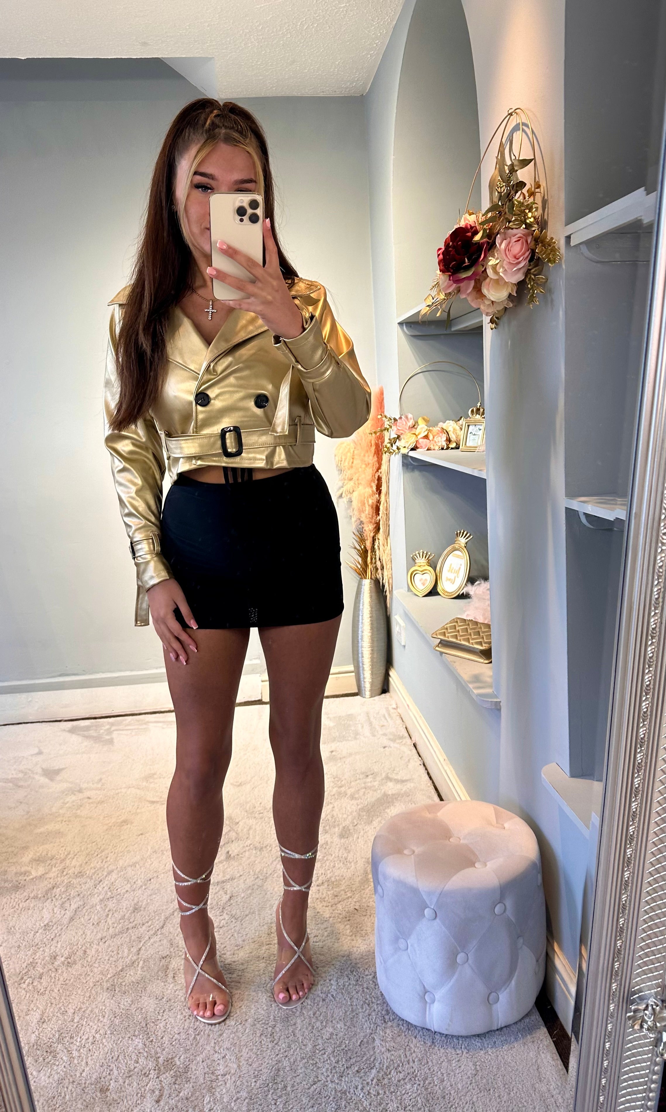 Woman modeling a gold belted cropped jacket with a black mini skirt and rhinestone lace-up heels — stylish and trendy party outfit for women