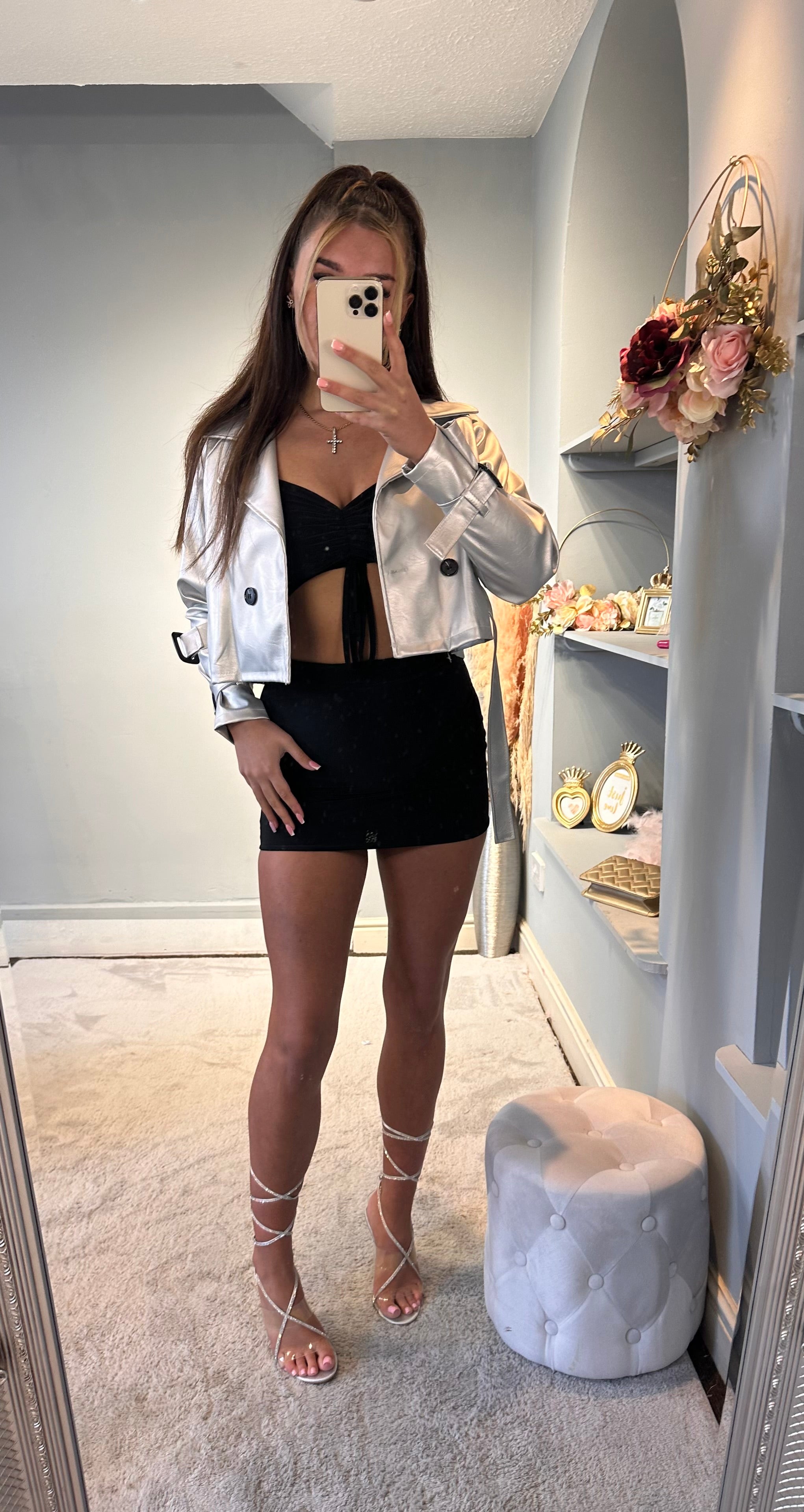 Woman wearing a silver cropped jacket paired with a black mini skirt and rhinestone lace-up heels — chic and modern party outfit for women