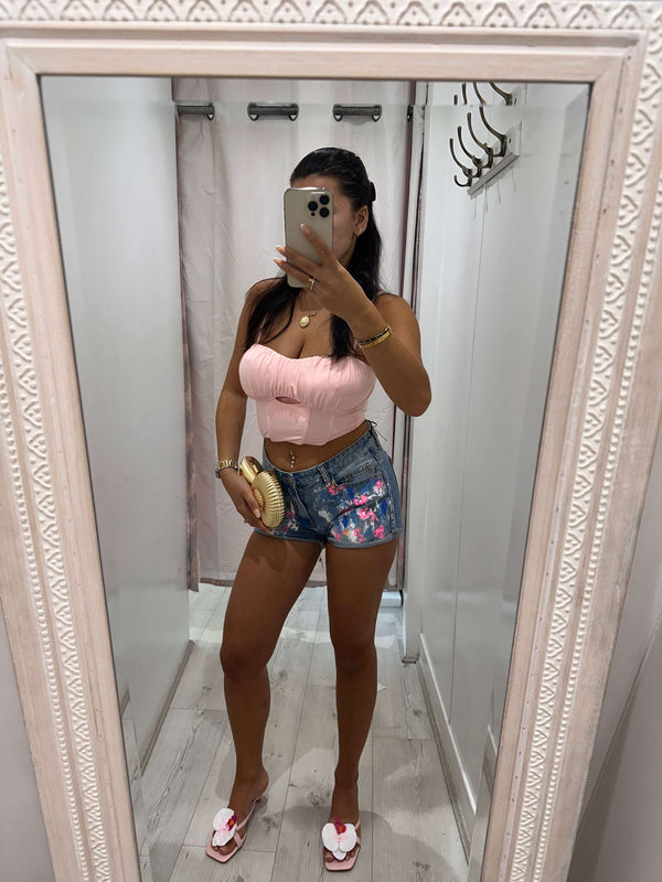 Woman wearing ANGEL Painted Denim Shorts with floral design on a sunny day