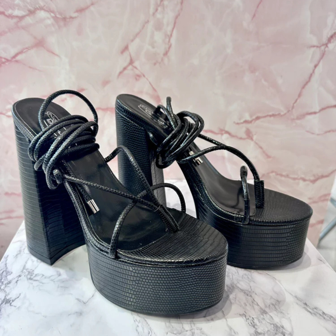 Black lizard print platform heels with ankle tie-up straps and chunky block heel, bold and elegant women’s footwear on marble background