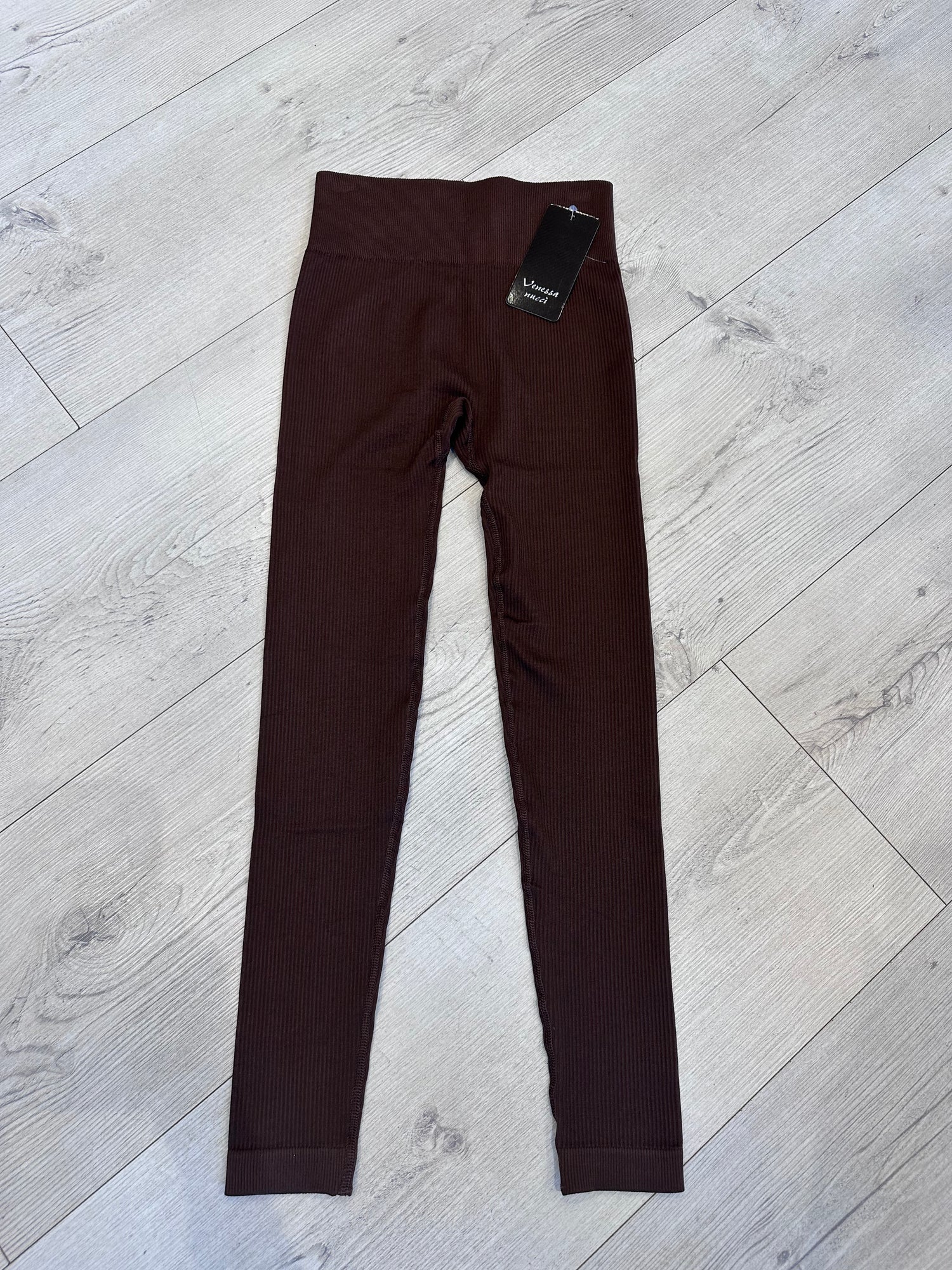 Chocolate brown ribbed high-waist leggings for women laid flat on a light wood background, showcasing seamless stretch fit and soft textured fabric