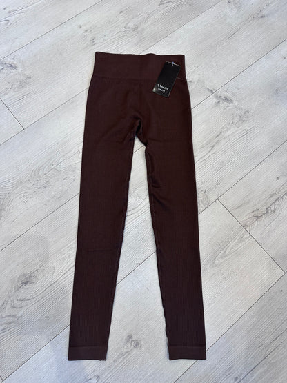 Chocolate brown ribbed high-waist leggings for women laid flat on a light wood background, showcasing seamless stretch fit and soft textured fabric