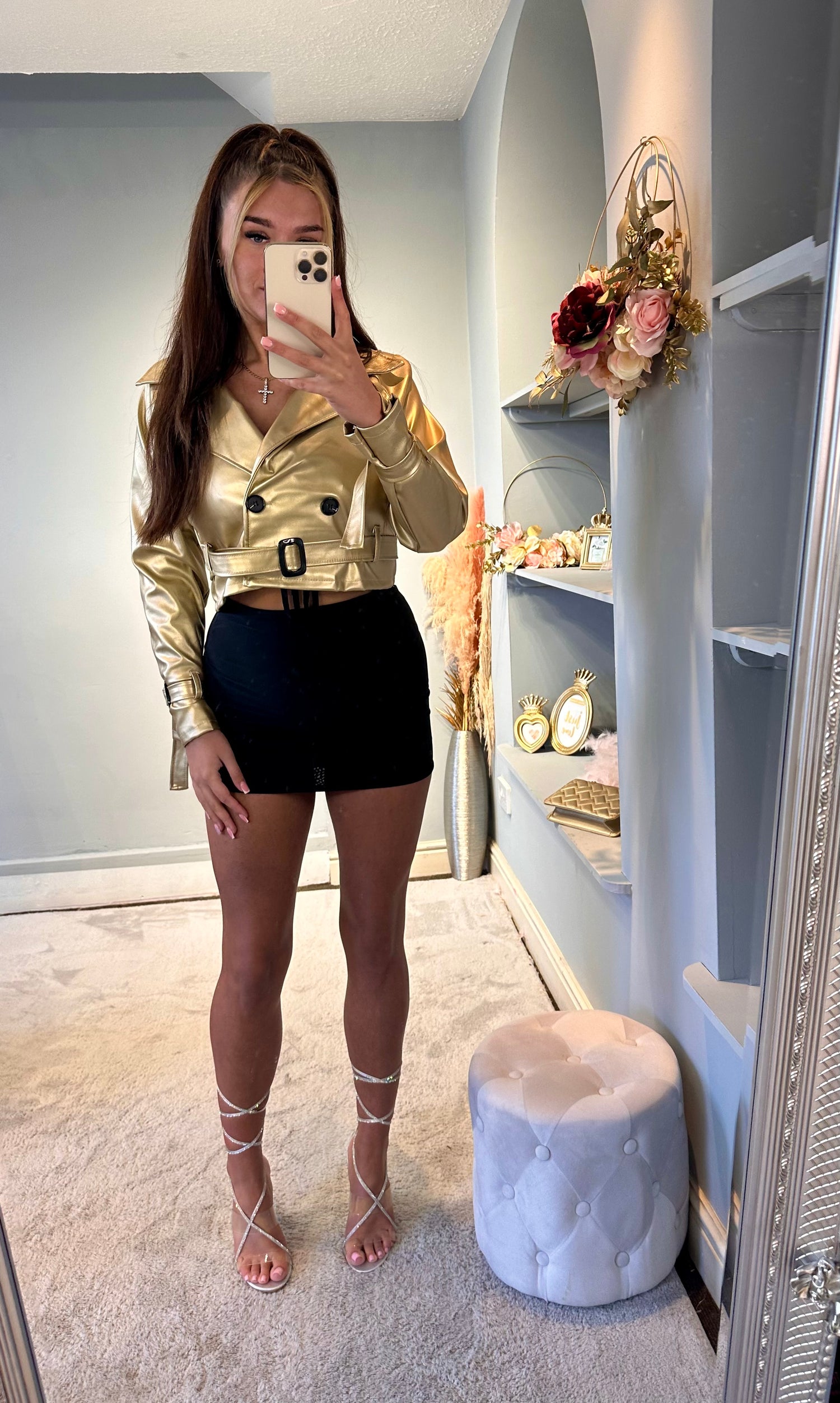 Woman modeling a gold belted cropped jacket with a black mini skirt and rhinestone lace-up heels — stylish and trendy party outfit for women